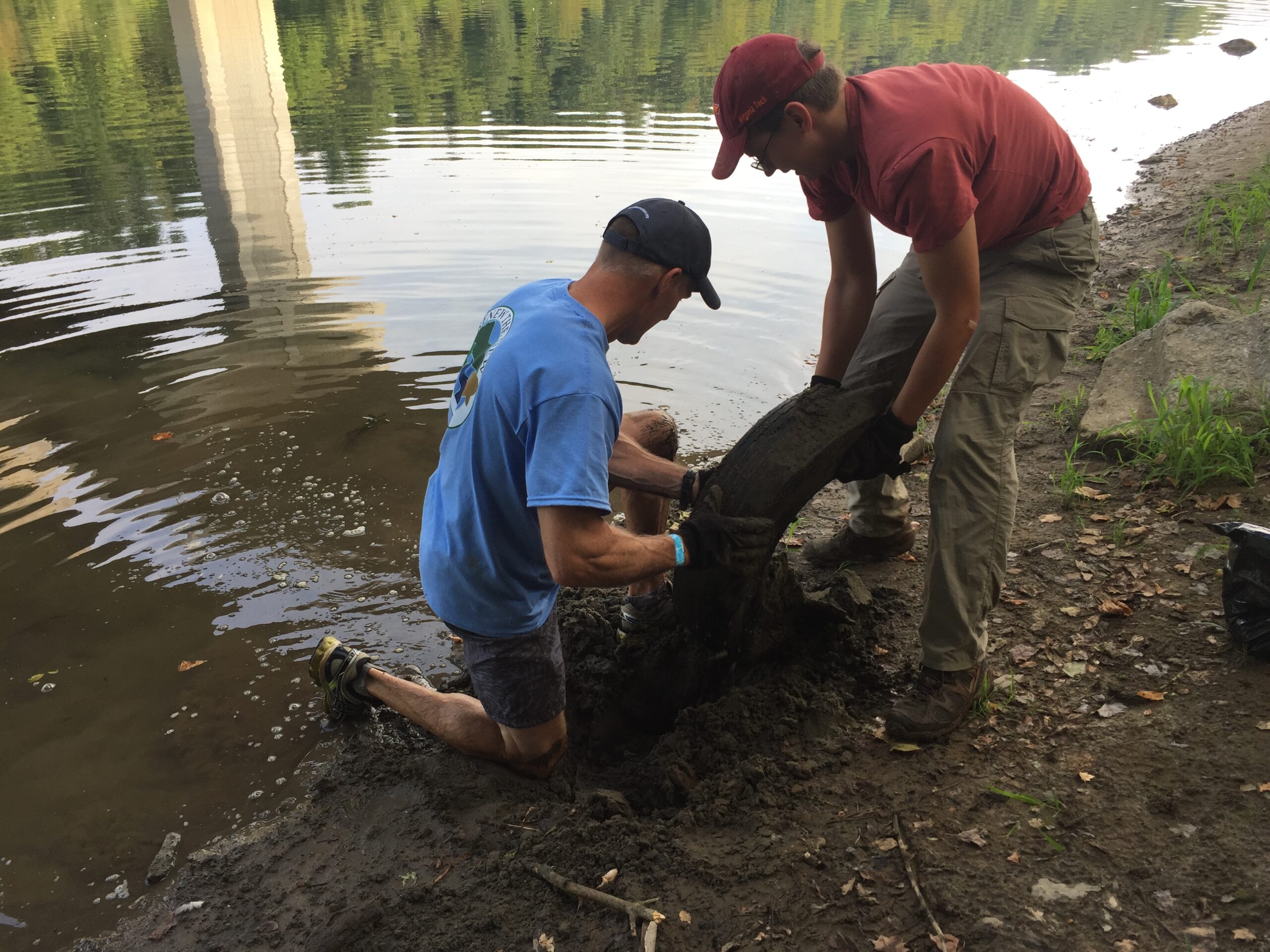 Two men pull tire from river