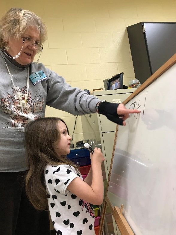 Woman poses with child at whiteboard