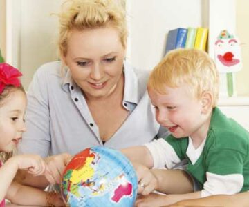 Woman and two children look at globe